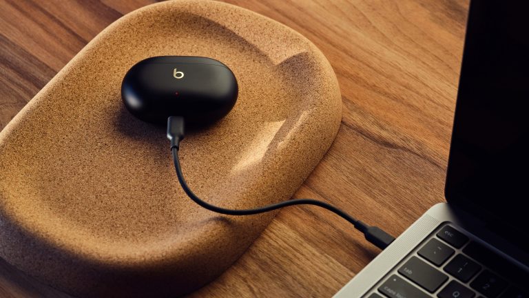 Ein Ladecase der Beats Studio Buds + ist per Kabel mit einem MacBook verbunden. Am Ladecase weist eine rot leuchtende LED auf den Ladevorgang hin. Ein Ladecase der Beats Studio Buds + ist per Kabel mit einem MacBook verbunden. Am Ladecase weist eine rot leuchtende LED auf den Ladevorgang hin.
