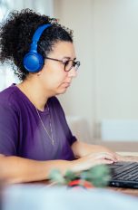 Eine Person mit Kopfhörern sitzt vor einem Laptop.