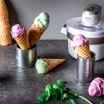 Mehrere Eiswaffeln stehen neben einer Eismaschine auf einem Tisch.