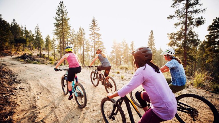 Eine Gruppe von Radfahrer*innen ist auf einem unbefestigten Weg in den Bergen unterwegs.