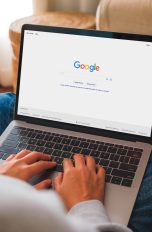 Eine Person mit einem MacBook auf dem Schoß hat die Google-Suche geöffnet.