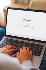 Eine Person hat einen Mac, auf dem die Google-Website geöffnet ist, auf dem Schoß.