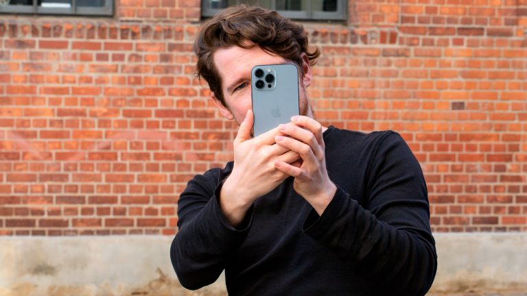 Eine Person hält ein iPhone 13 Pro Max Richtung Kamera.