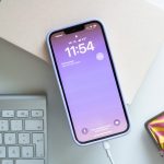 Ein iPhone 13 liegt zwischen mehreren Deko-Elementen und wird über ein Lightning-Kabel aufgeladen.