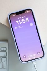 Ein iPhone 13 liegt zwischen mehreren Deko-Elementen und wird über ein Lightning-Kabel aufgeladen.