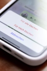 Nahaufnahme eines iPhone 13, auf dem gerade eine Nachricht bei WhatsApp gelöscht werden soll.