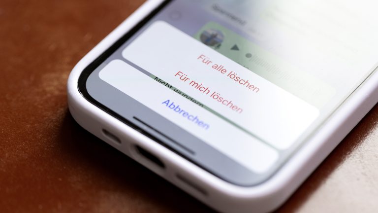 Nahaufnahme eines iPhone 13, auf dem gerade eine Nachricht bei WhatsApp gelöscht werden soll.