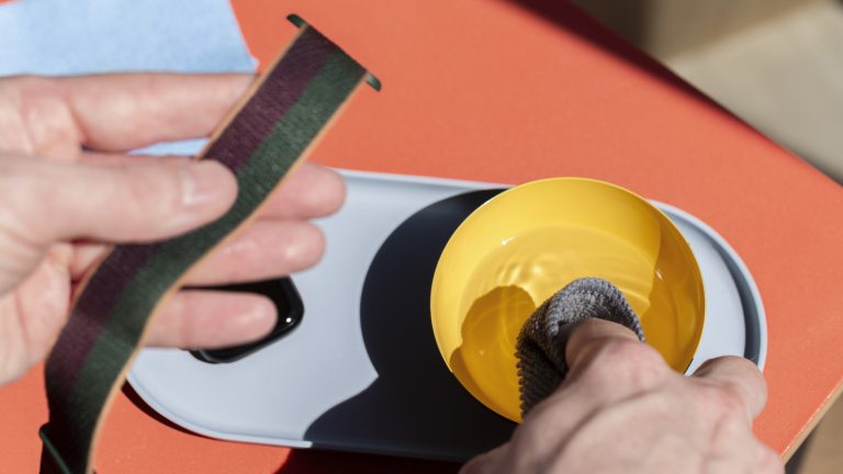 Eine Person feuchtet mit der rechten Hand ein Mikrofasertuch an, in der linken hält er ein Armband der Apple Watch.