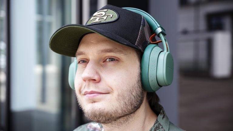 Eine Person hat die Fairbuds XL in Grün auf dem Kopf und schaut in die Ferne.