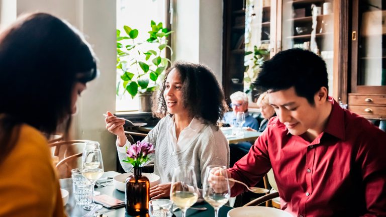 Mehrere Personen sitzen in einem Restaurant an einem Tisch und essen.