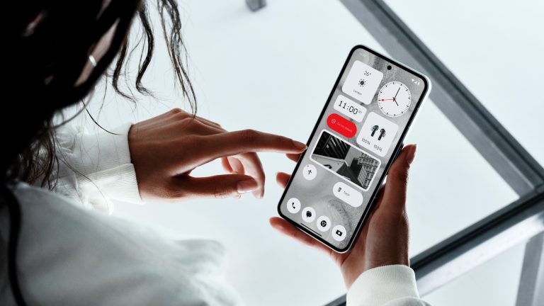Eine Person hält ein Nothing Phone (2) in den Händen. Darauf zu sehen ist der Homescreen mit einigen Widgets.