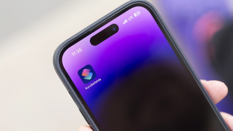 Nahaufnahme eines iPhone 14 Pro, auf dessen Home-Bildschirm die Kurzbefehle-App zu sehen ist.