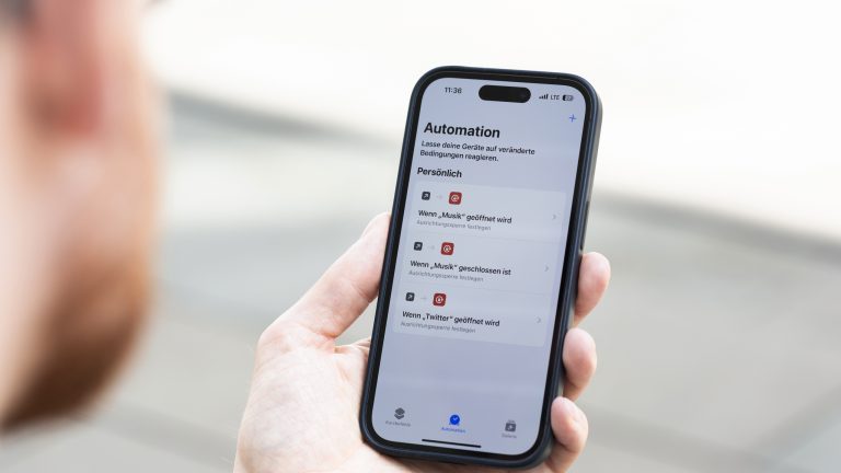 Eine Person hält ein iPhone 14 Pro in der Hand, auf dem gerade die Automation in der Kurzbefehle-App geöffnet ist.