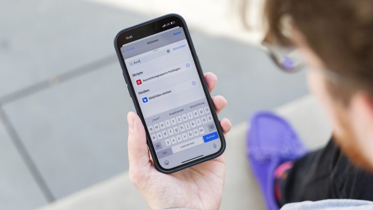 Eine Person hält ein iPhone 14 Pro in der Hand, auf dem gerade die Automation in der Kurzbefehle-App geöffnet ist.