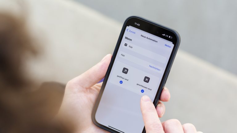 Eine Person hält ein iPhone 14 Pro in der Hand, auf dem gerade die Automation in der Kurzbefehle-App geöffnet ist.