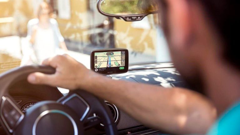 Eine Person sitzt in einem Auto und schaut auf die Routenführung des Navigationssystems.
