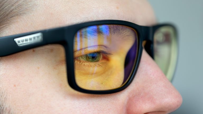 Nahaufnahme einer Computerbrille, deren Gläser blaues Licht spiegeln.