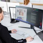 Eine Person sitzt in einem Büro vor einem Ultrawide-Monitor.