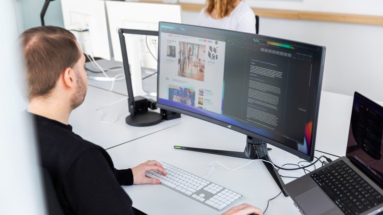 Eine Person sitzt in einem Büro vor einem Ultrawide-Monitor.