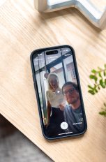 Ein iPhone 14 Pro liegt auf einem Holztisch. Auf dem Bildschirm ist eine Videonachricht bei FaceTime zu sehen.