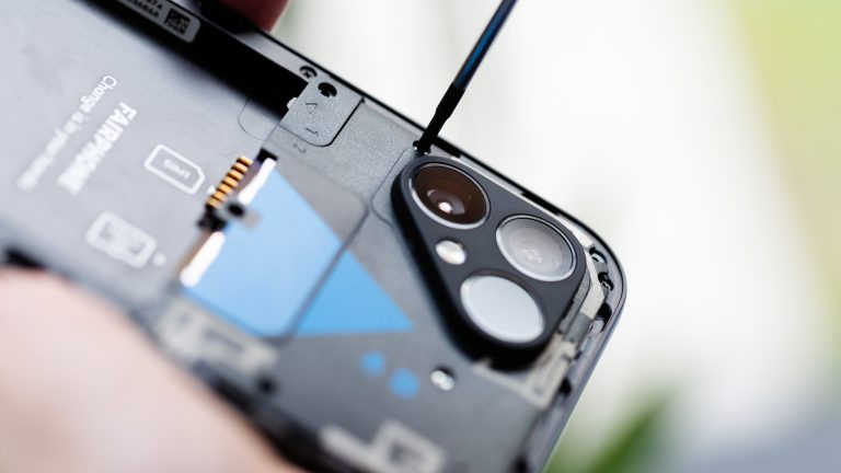 Nahaufnahme eines geöffneten Fairphone 5, bei dem eine Person gerade die Top-Einheit abschraubt. Nahaufnahme eines geöffneten Fairphone 5, bei dem eine Person gerade die Top-Einheit abschraubt.