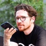 Eine Person hält ein Smartphone vor ihr Gesicht und nimmt eine Sprachnachricht auf.