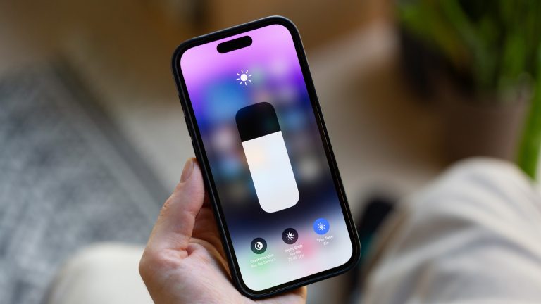 Eine Person hält ein iPhone in der Hand, auf dem gerade die Optionen für den Dunkelmodus im Kontrollzentrum geöffnet sind.