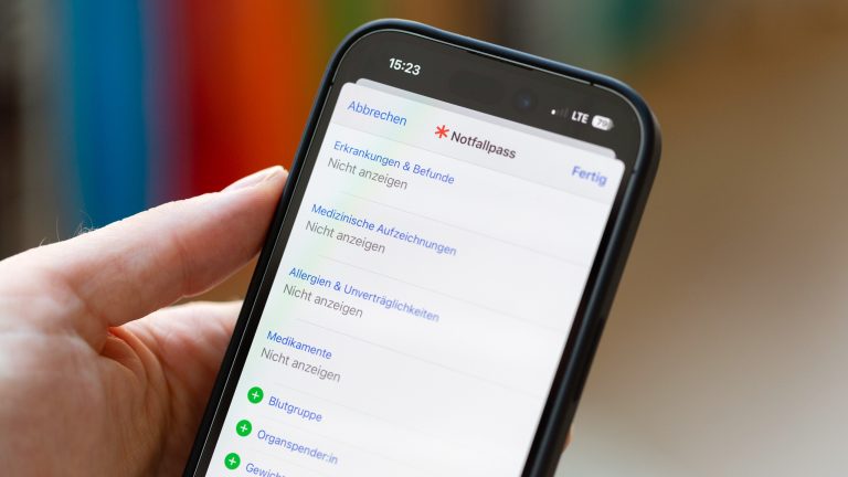 Eine Person hält ein iPhone in die Kamera, auf der ein Notfallpass zu sehen ist.