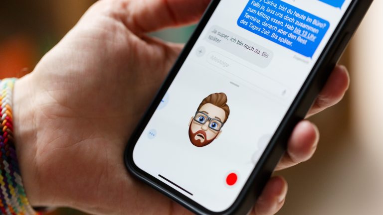 Eine Person hält ein iPhone in der Hand, auf der ein Memoji den Gesichtsausdruck der Person nachahmt.