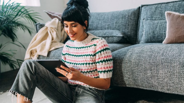 Eine Person sitzt vor einem Sofa auf dem Boden und hält ein iPhone in der Hand.
