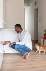 Eine Person hockt vor einem geöffneten Gefrierschrank.