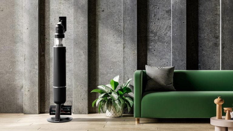 Ein Samsung Bespoke Jet AI steht neben einem Sofa in einem Wohnzimmer.