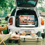 Zwei Personen sitzen vor dem Kofferaum eines Autos. Darin ist der portable Fernseher StandbyMe Go von LG zu sehen.