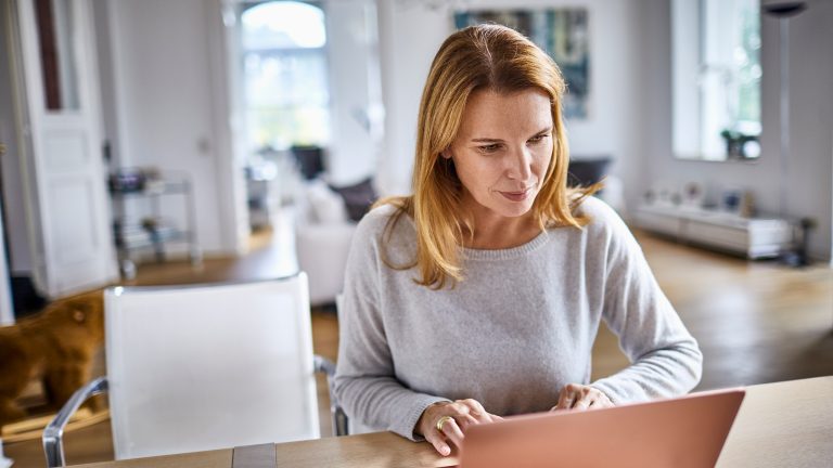 Eine Person sitzt an einem Tisch vor einem Laptop. Eine Person sitzt an einem Tisch vor einem Laptop.