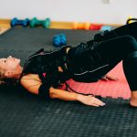 Eine Person macht eine Übung auf dem Boden und trägt dabei EMS-Ausrüstung.