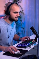 Eine Person mit einem Kopfhörer auf dem Kopf sitzt vor einem Gaming-PC und spielt etwas.