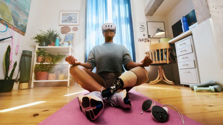 Eine Person sitzt im Schneidersitz auf einer Fitnessmatte. Vor den Augen trägt die Person eine Meta Quest 3. Eine Person sitzt im Schneidersitz auf einer Fitnessmatte. Vor den Augen trägt die Person eine Meta Quest 3.