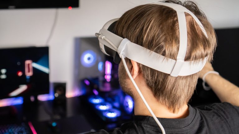 Eine Person trägt eine Meta Quest 3 auf dem Kopf, die per Kabel an einen Rechner angeschlossen ist. Darauf läuft Beat Saber.