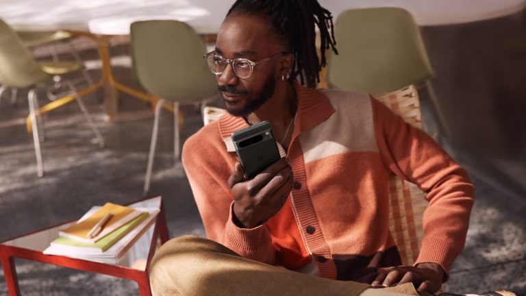 Eine Person sitzt in einem Sessel und hält ein Google Pixel 8 Pro in der Hand.