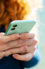 Eine Person hält ein Smartphone in der Hand und tippt mit beiden Daumen auf das Display.