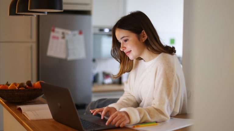 Eine Person steht in einer Küche und arbeitet an einem MacBook.