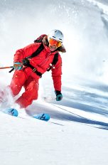 Eine Person fährt auf Skiern im Slalom eine Piste hinunter.