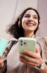 Eine Person hält ein iPhone in der Hand und hört auf angeschlossenen Kopfhörern etwas.