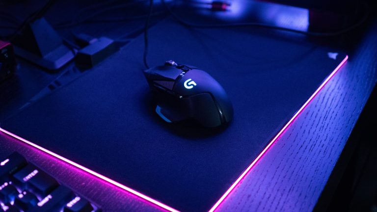 Eine Logitech G502 liegt auf einem beleuchteten Mauspad von Corsair.