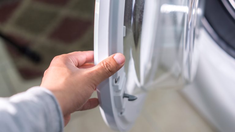 Waschmaschine zieht kein Wasser: So läuft sie wieder Eine Person öffnet die Tür an einer Waschmaschine.