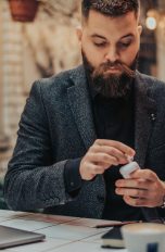 Eine Person sitzt in einem Café und steckt ihre AirPods wieder in das Case.