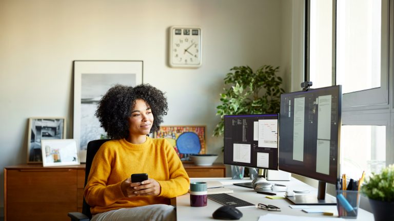 Eine Person sitzt in einem Office-Setup vor einem Rechner mit zwei Monitoren.