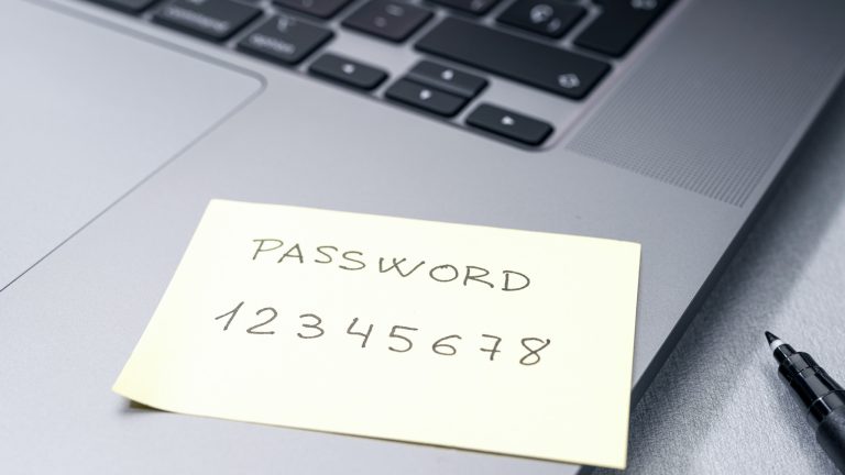 Post-it, auf dem “PASSWORD 12345678” notiert wurde, klebt auf einem Laptop.