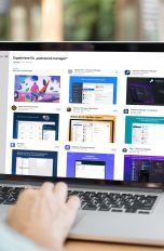 Person sitzt mit einem MacBook im Freien. Auf dem Bildschirm ist der Apple Appstore mit einer Übersicht von Passwort-Managern geöffnet.