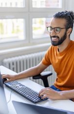 Eine Person sitzt in einem Büro vor zwei Monitoren.
